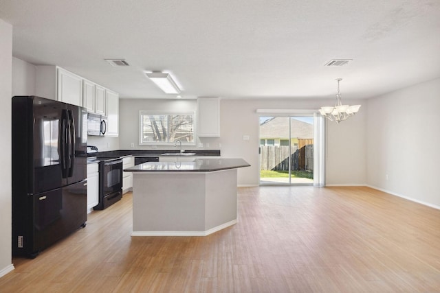 kitchen featuring sink, white cabinetry, a center island, hanging light fixtures, and black appliances