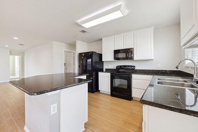 kitchen with sink, dark stone countertops, white cabinets, black appliances, and light hardwood / wood-style flooring