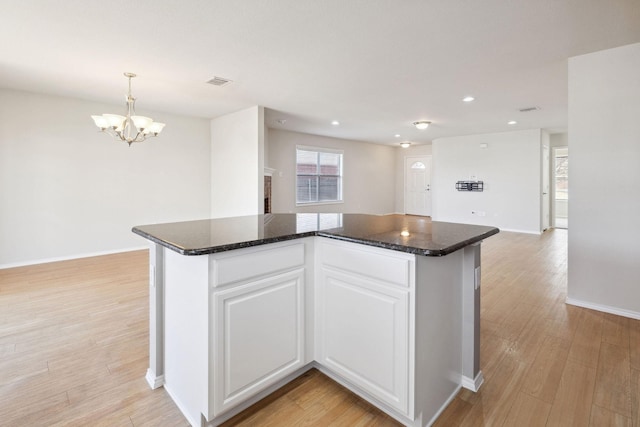 kitchen featuring pendant lighting, white cabinetry, a notable chandelier, light hardwood / wood-style floors, and a kitchen island