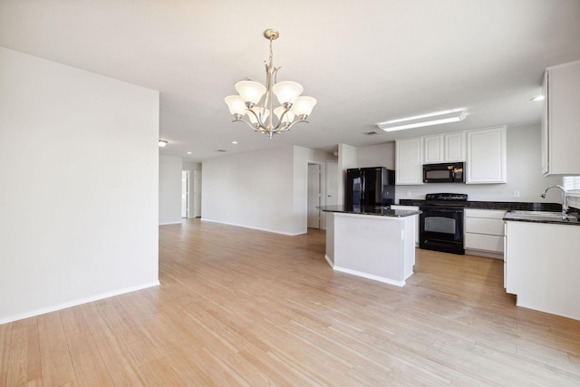 kitchen featuring sink, white cabinets, hanging light fixtures, black appliances, and light hardwood / wood-style flooring