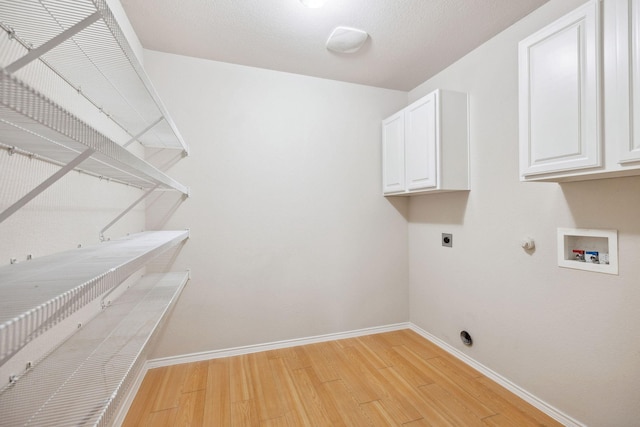 washroom featuring gas dryer hookup, electric dryer hookup, cabinets, washer hookup, and light hardwood / wood-style floors