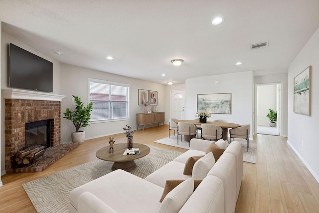 living room featuring a brick fireplace and light hardwood / wood-style floors