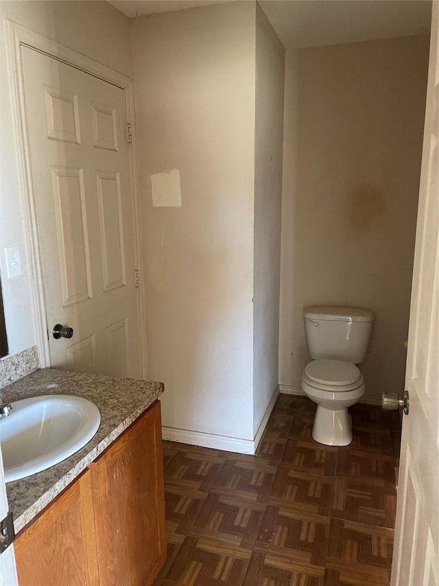 bathroom with vanity, parquet flooring, and toilet