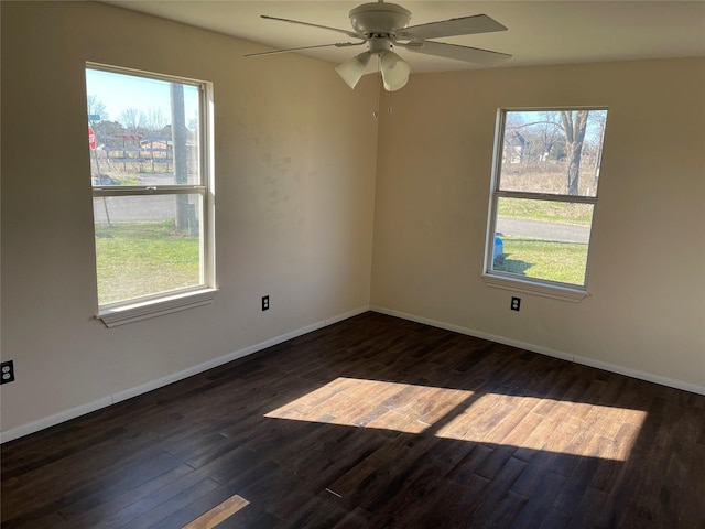 spare room with dark hardwood / wood-style flooring, ceiling fan, and a healthy amount of sunlight