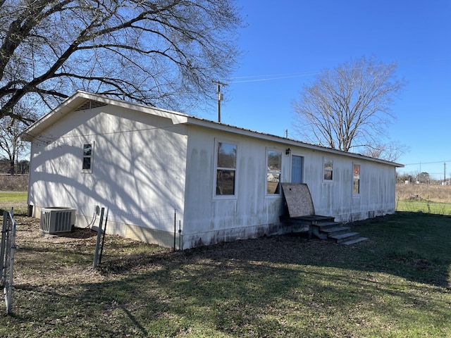 rear view of property featuring cooling unit and a yard