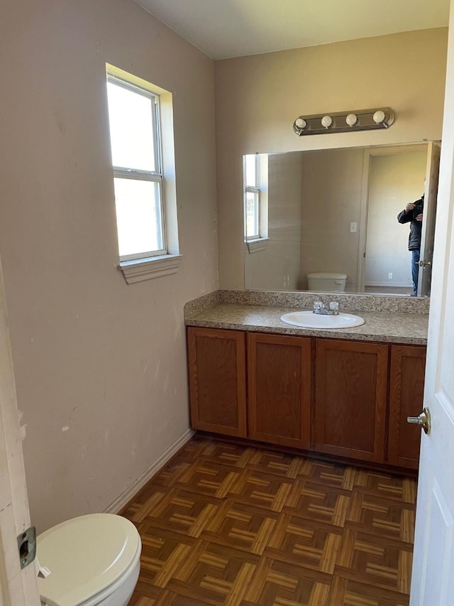 bathroom featuring parquet floors, vanity, and toilet