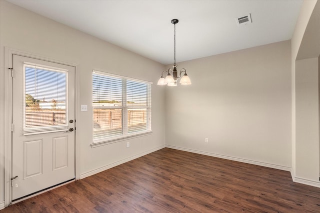 unfurnished dining area featuring a chandelier and dark hardwood / wood-style flooring