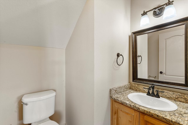 bathroom with lofted ceiling, toilet, and vanity