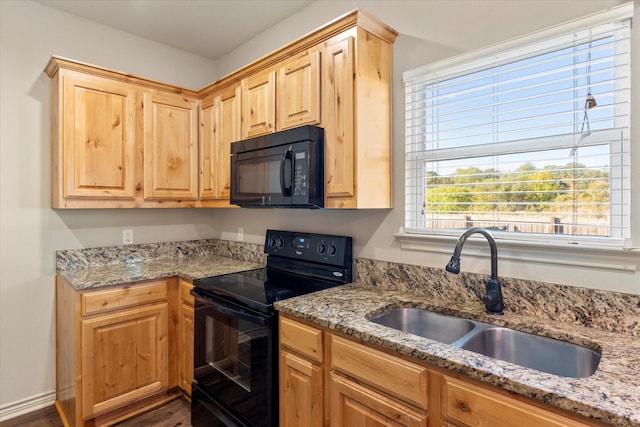 kitchen with light stone counters, sink, black appliances, and light brown cabinetry