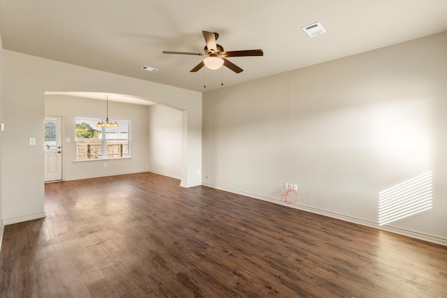 empty room with dark hardwood / wood-style flooring and ceiling fan with notable chandelier