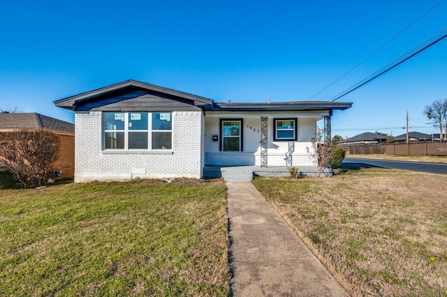 view of front of property with covered porch, brick siding, fence, and a front lawn