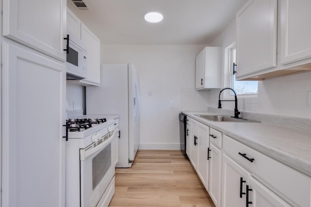 kitchen featuring light countertops, visible vents, a sink, light wood-type flooring, and white appliances