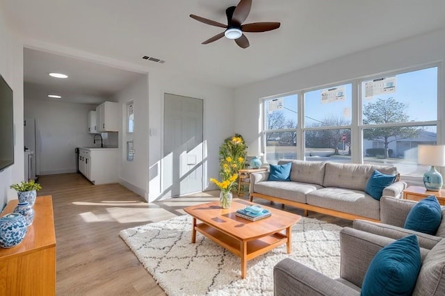 living room featuring light hardwood / wood-style flooring, ceiling fan, and sink