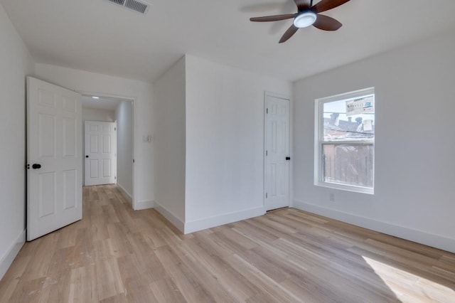 empty room featuring baseboards, a ceiling fan, visible vents, and light wood-style floors