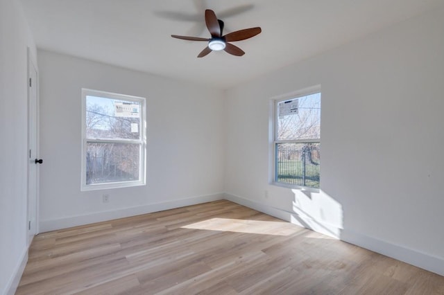 spare room with light wood-type flooring, a wealth of natural light, and ceiling fan