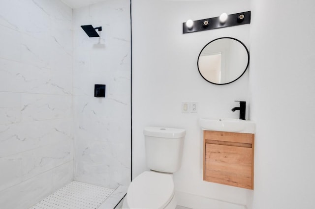 bathroom with toilet, tiled shower, and vanity