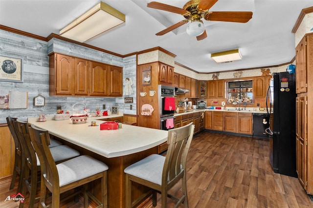 kitchen with black appliances, dark hardwood / wood-style flooring, a kitchen bar, kitchen peninsula, and crown molding