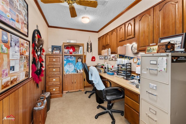 office featuring built in desk, light carpet, a textured ceiling, ornamental molding, and wooden walls