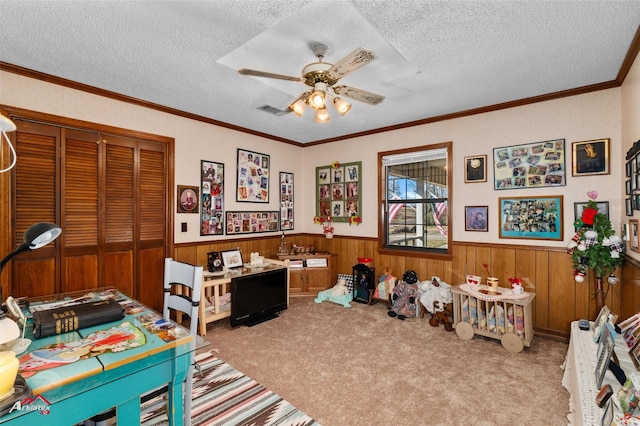 game room with ceiling fan, light colored carpet, ornamental molding, and a textured ceiling