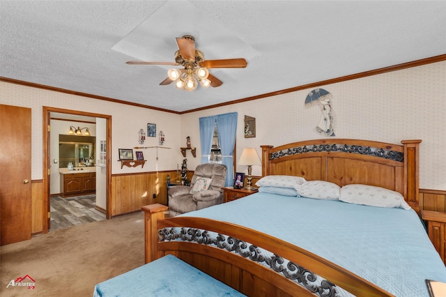 carpeted bedroom featuring crown molding, ceiling fan, ensuite bathroom, and sink