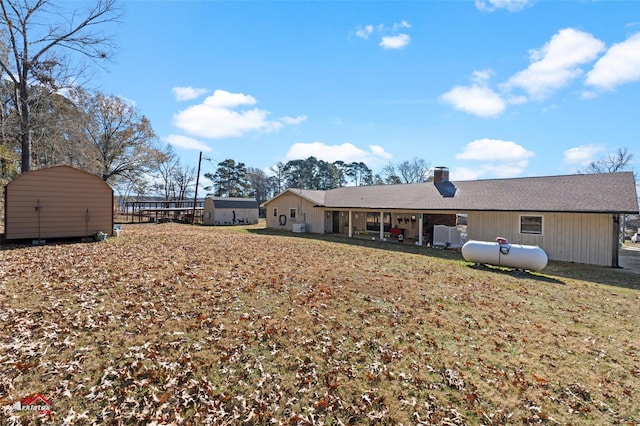 rear view of house featuring a storage shed and a yard