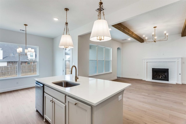 kitchen with a fireplace, light wood-style floors, arched walkways, and a sink