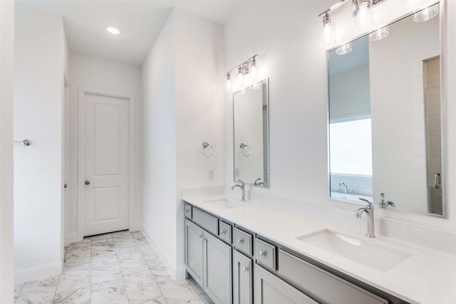 bathroom with double vanity, marble finish floor, baseboards, and a sink