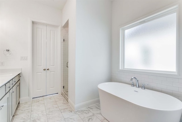 bathroom with vanity, baseboards, a soaking tub, a shower stall, and marble finish floor