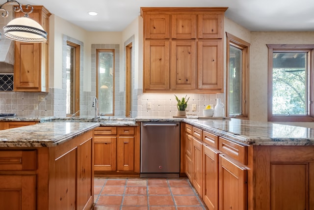 kitchen featuring decorative light fixtures, dishwasher, backsplash, a center island, and light stone counters