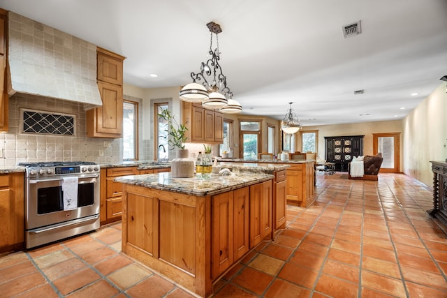 kitchen featuring backsplash, hanging light fixtures, a center island, light tile patterned floors, and gas range