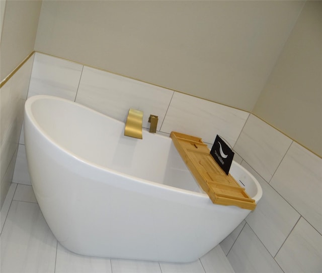 bathroom with tile walls, a tub to relax in, and tile patterned floors