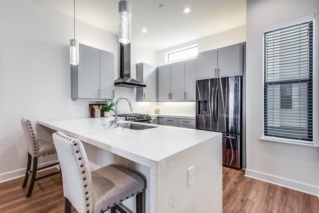 kitchen with gray cabinets, stainless steel refrigerator with ice dispenser, pendant lighting, and kitchen peninsula