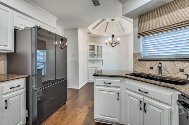 kitchen with sink, stainless steel fridge, hanging light fixtures, white cabinets, and a chandelier