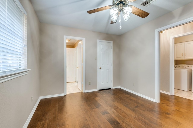 unfurnished bedroom with washer / dryer, ceiling fan, and hardwood / wood-style flooring