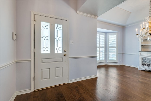 foyer featuring lofted ceiling, a notable chandelier, ornamental molding, and dark hardwood / wood-style floors