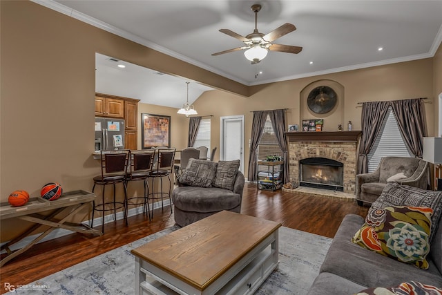 living room featuring dark hardwood / wood-style flooring, crown molding, vaulted ceiling, and a stone fireplace