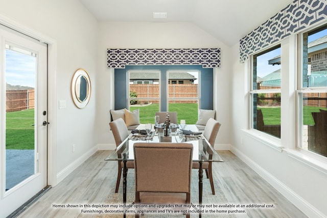 dining space featuring light hardwood / wood-style flooring, vaulted ceiling, and plenty of natural light