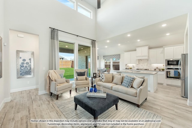 living room featuring a towering ceiling, light hardwood / wood-style floors, and sink