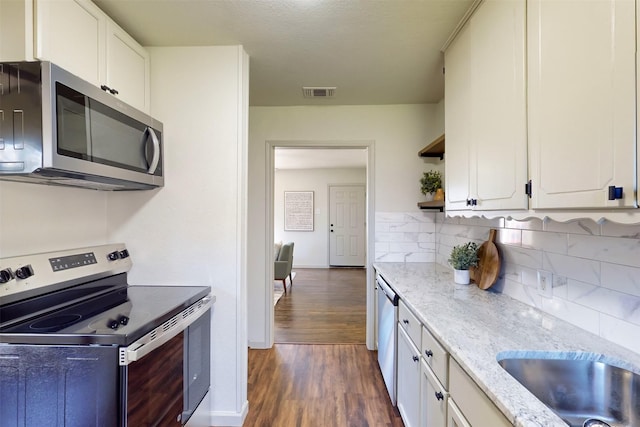 2842 Carlson Dr, Dallas, TX 75235 - kitchen featuring tasteful backsplash, appliances with stainless steel finishes, dark wood-type flooring, and white cabinets