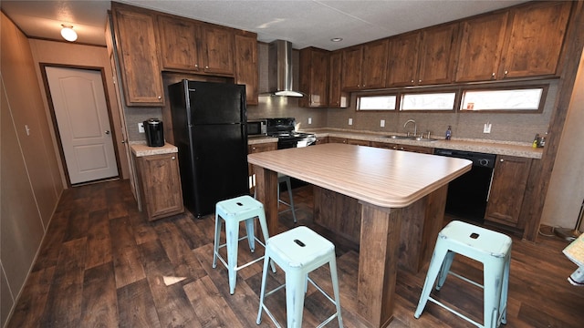 kitchen with a kitchen island, a breakfast bar, sink, black appliances, and wall chimney range hood