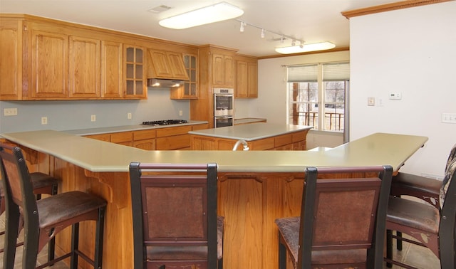 kitchen featuring a breakfast bar area, a center island, track lighting, kitchen peninsula, and stainless steel appliances