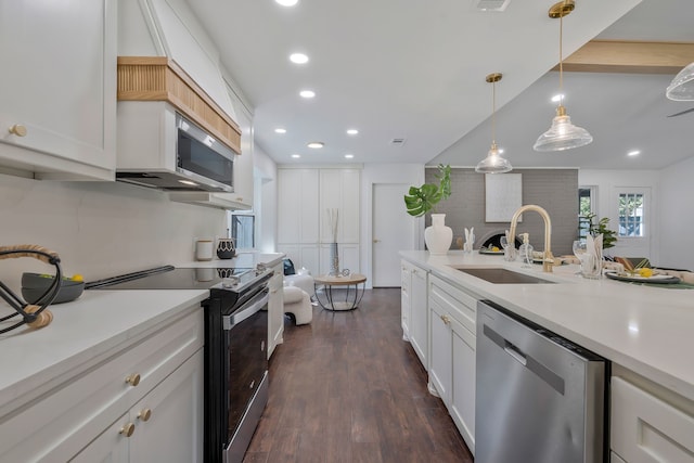 kitchen with appliances with stainless steel finishes, sink, white cabinets, hanging light fixtures, and dark wood-type flooring