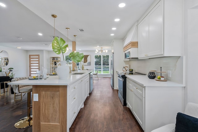 kitchen with stainless steel appliances, white cabinetry, and an island with sink