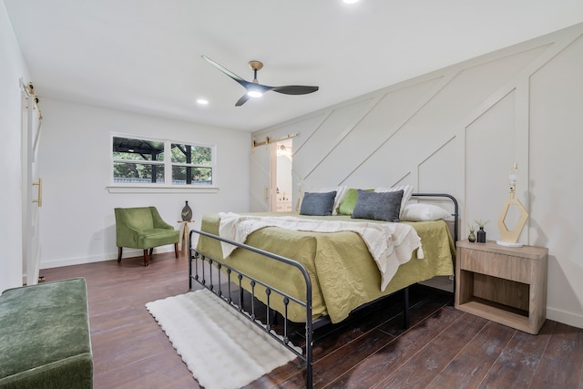 bedroom with dark wood-type flooring, ceiling fan, and a barn door