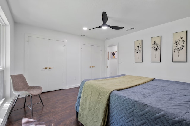 bedroom with dark hardwood / wood-style flooring, two closets, and ceiling fan