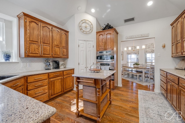 kitchen with backsplash, hanging light fixtures, wood-type flooring, and a center island