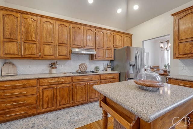 kitchen with tasteful backsplash, a kitchen island, black electric cooktop, and stainless steel refrigerator with ice dispenser