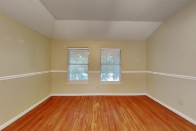 empty room featuring hardwood / wood-style flooring and vaulted ceiling