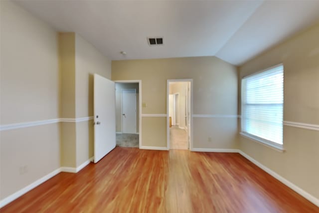 unfurnished bedroom featuring vaulted ceiling and hardwood / wood-style floors