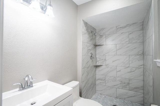 bathroom featuring vanity, toilet, and tiled shower